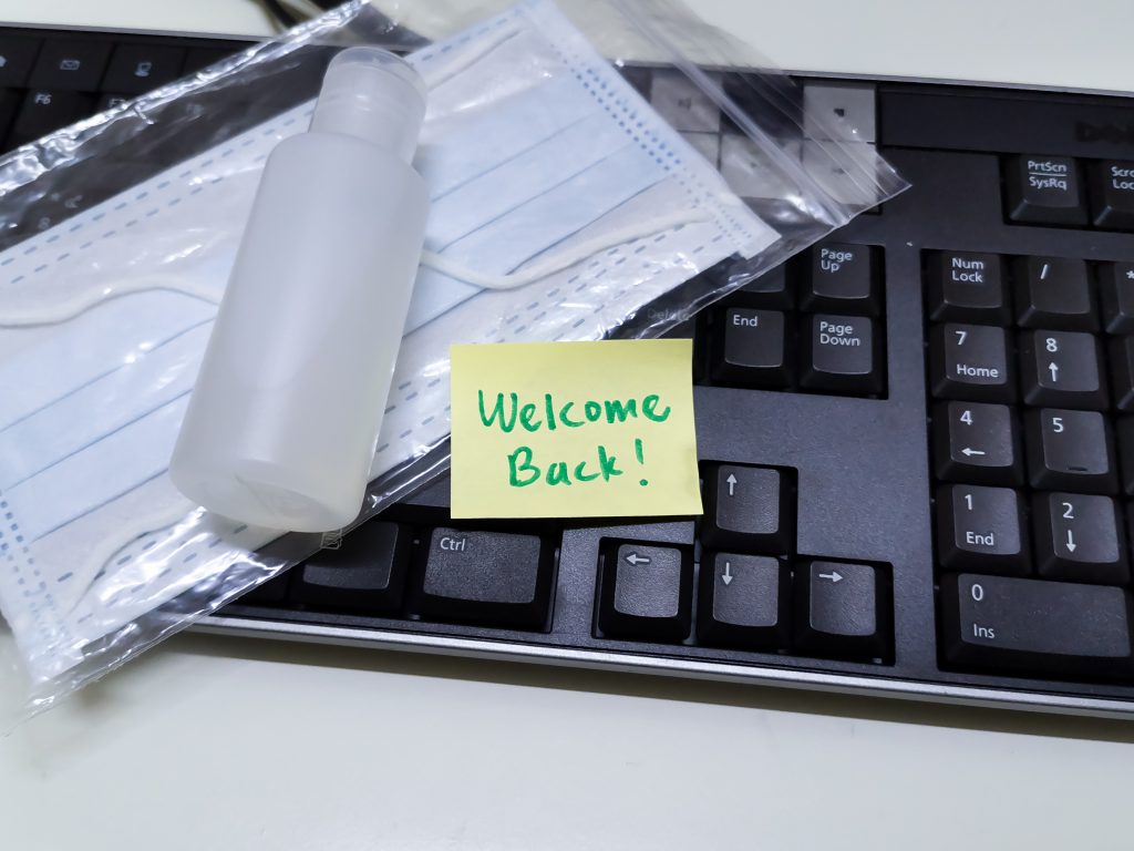 Welcome,Back,Note,With,Hand,Sanitizer,And,Mask,On,Work