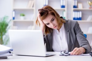 return to work wellbeing woman with head in hands at desk